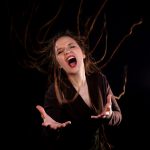 NaDur Sängerin in schwarzem Raum ruft ausdrucksstark