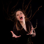 NaDur Sängerin in schwarzem Raum ruft ausdrucksstark